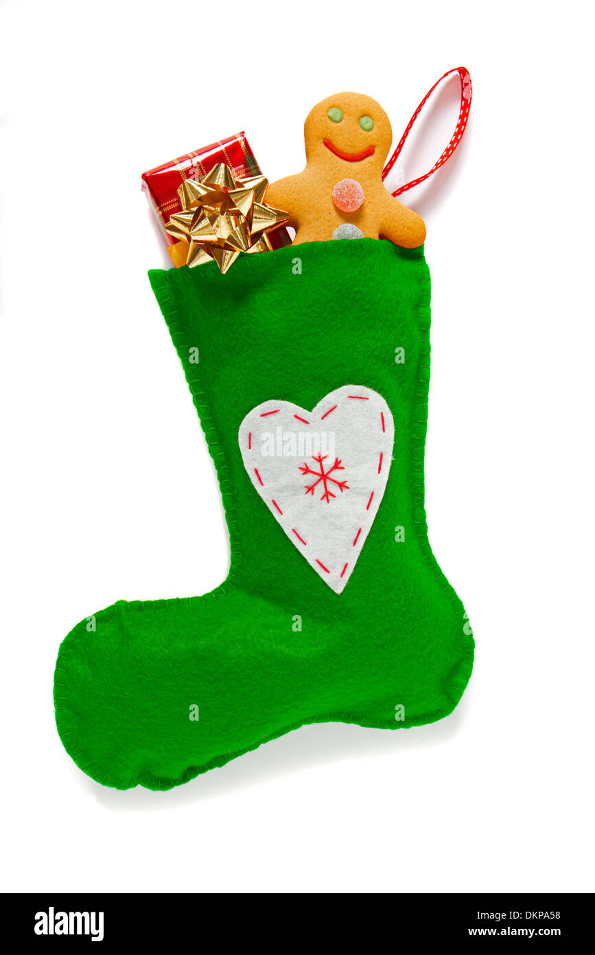 A green handmade Christmas stocking with gift and gingerbread man, isolated on a white background. Stock Photo