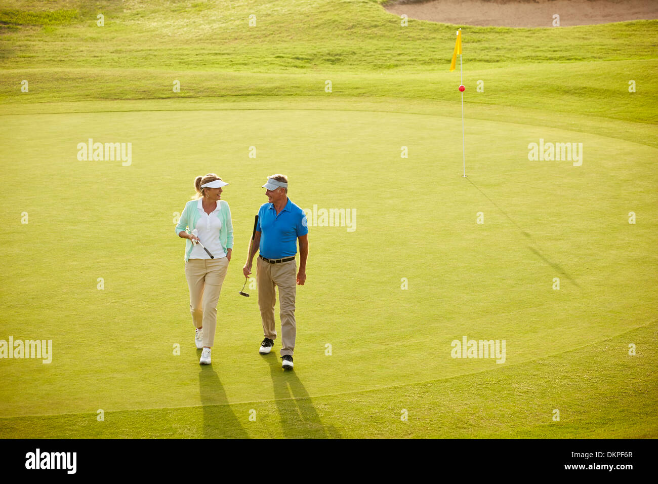 Senior couple walking on golf course Stock Photo