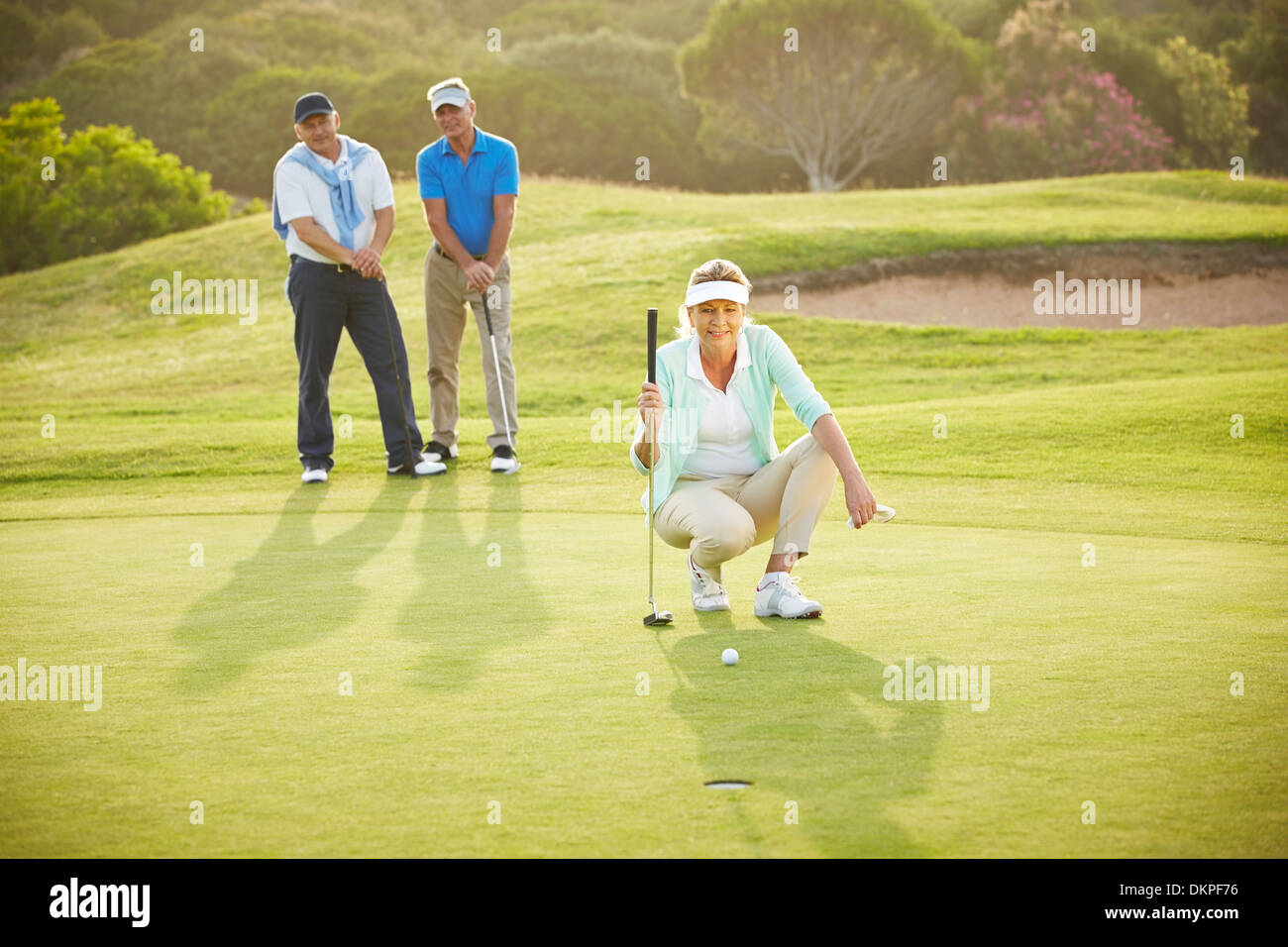 Senior friends playing golf on course Stock Photo