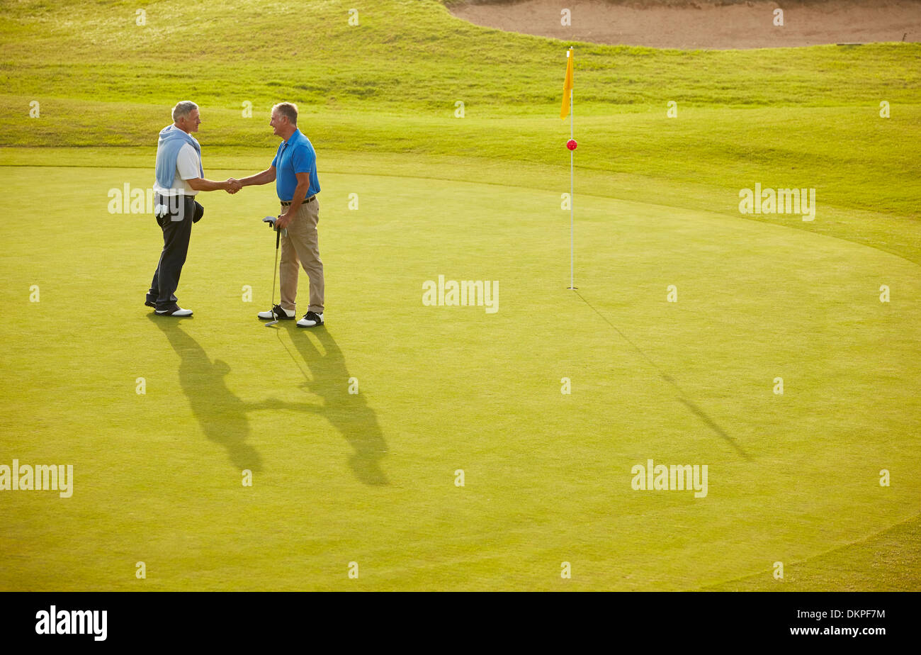 Senior men shaking hands on golf course Stock Photo