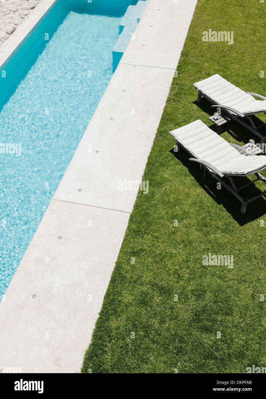 Lounge chairs on grass along lap pool Stock Photo - Alamy