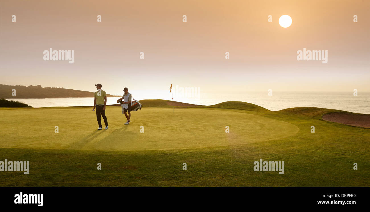 Golfer and caddy walking on golf course Stock Photo Alamy