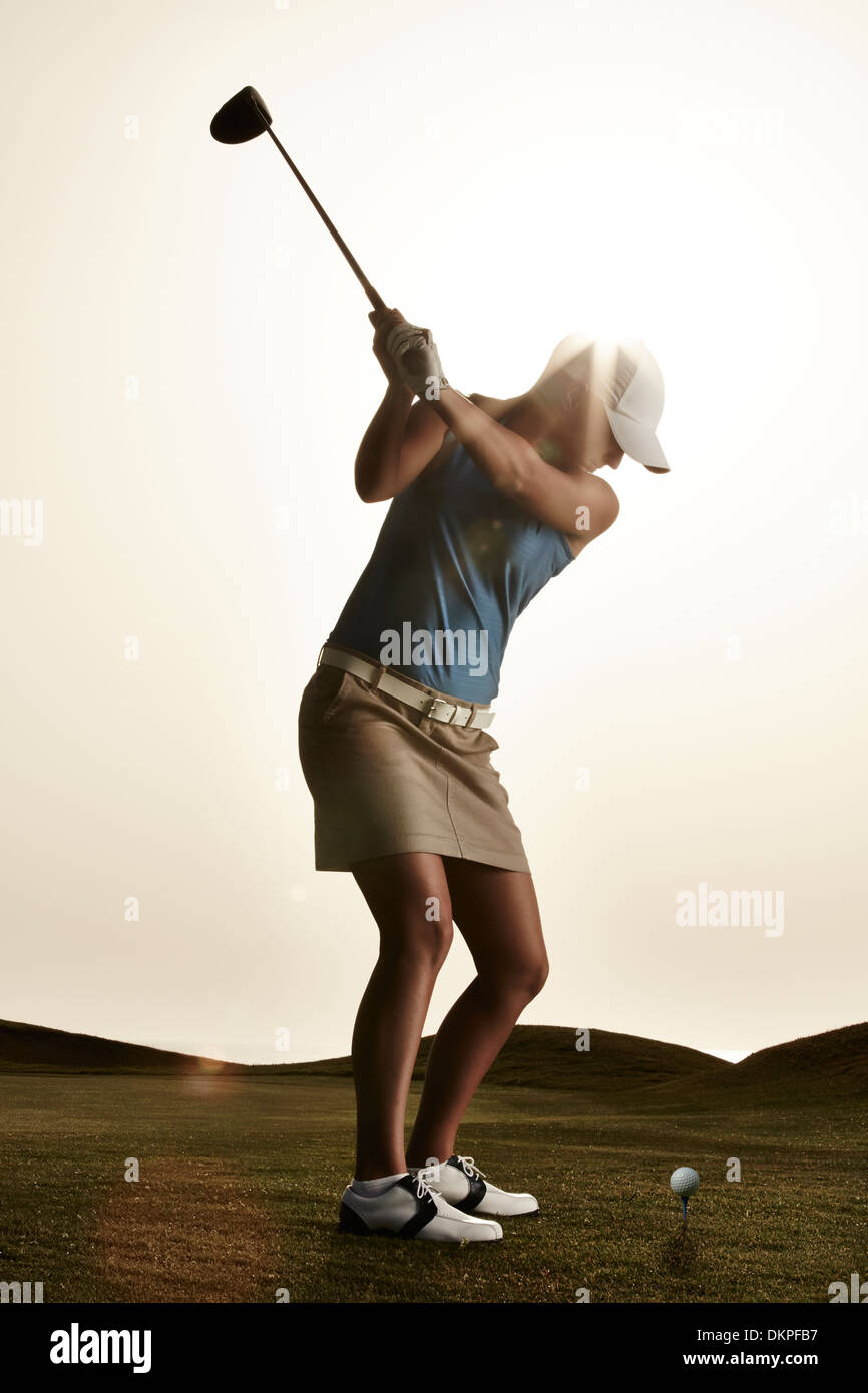 Woman swinging golf club Stock Photo
