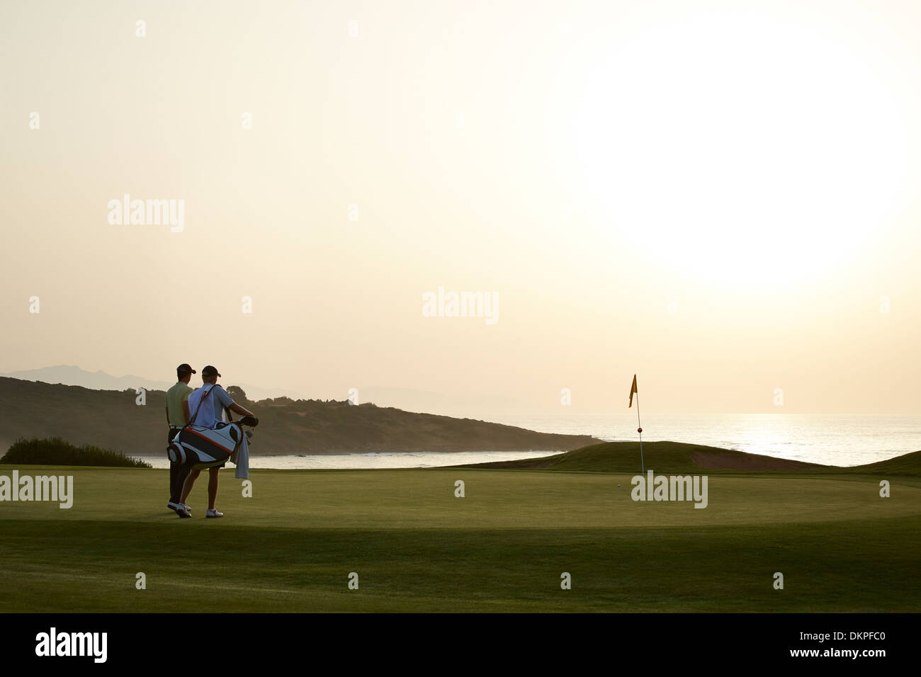 Men on golf course at sunset Stock Photo