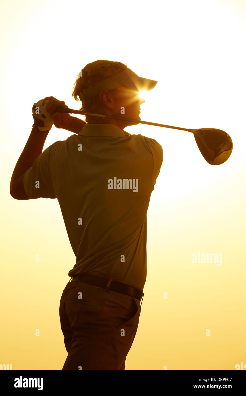 Silhouette of man swinging golf club Stock Photo