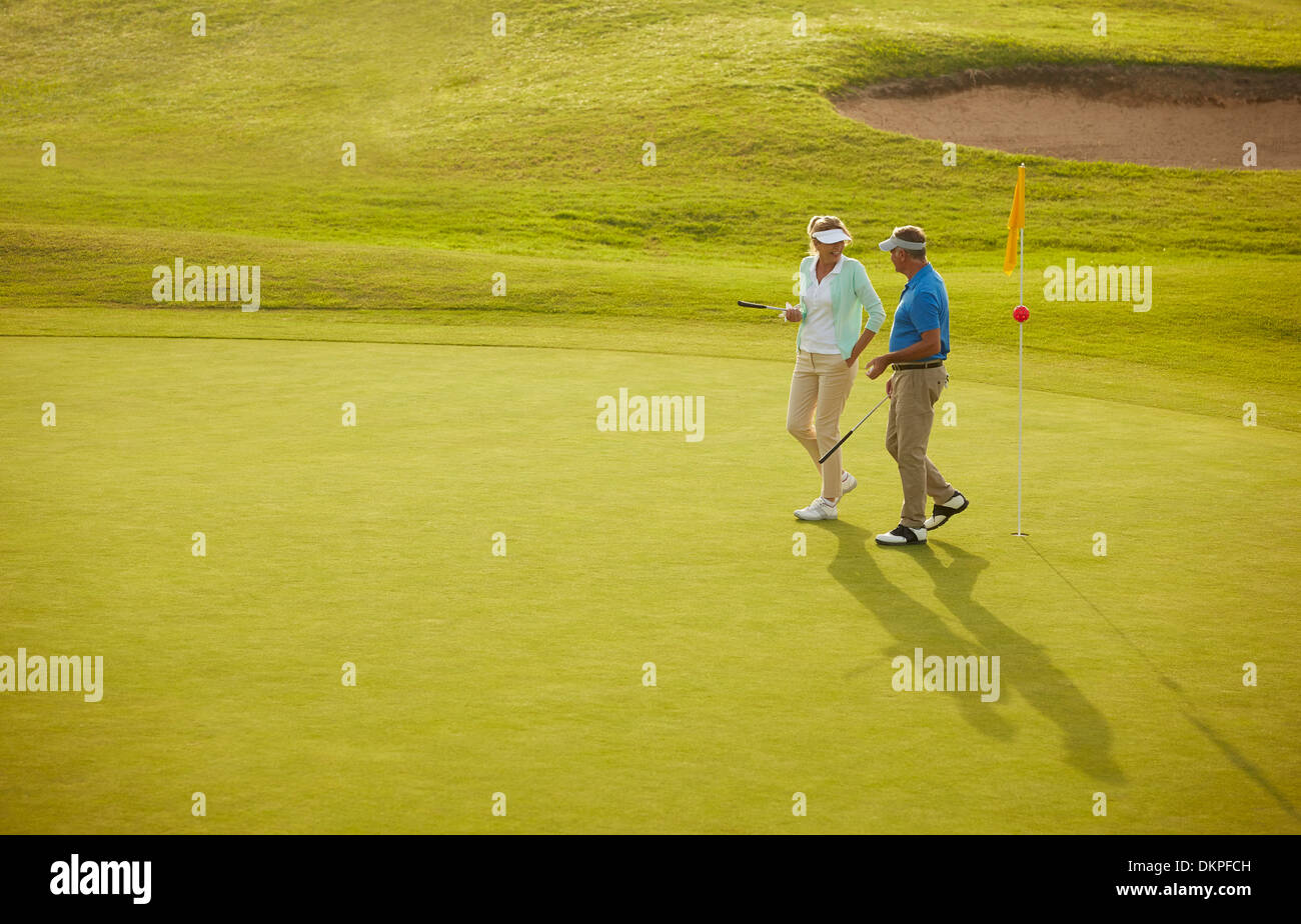 Senior couple walking on golf course Stock Photo