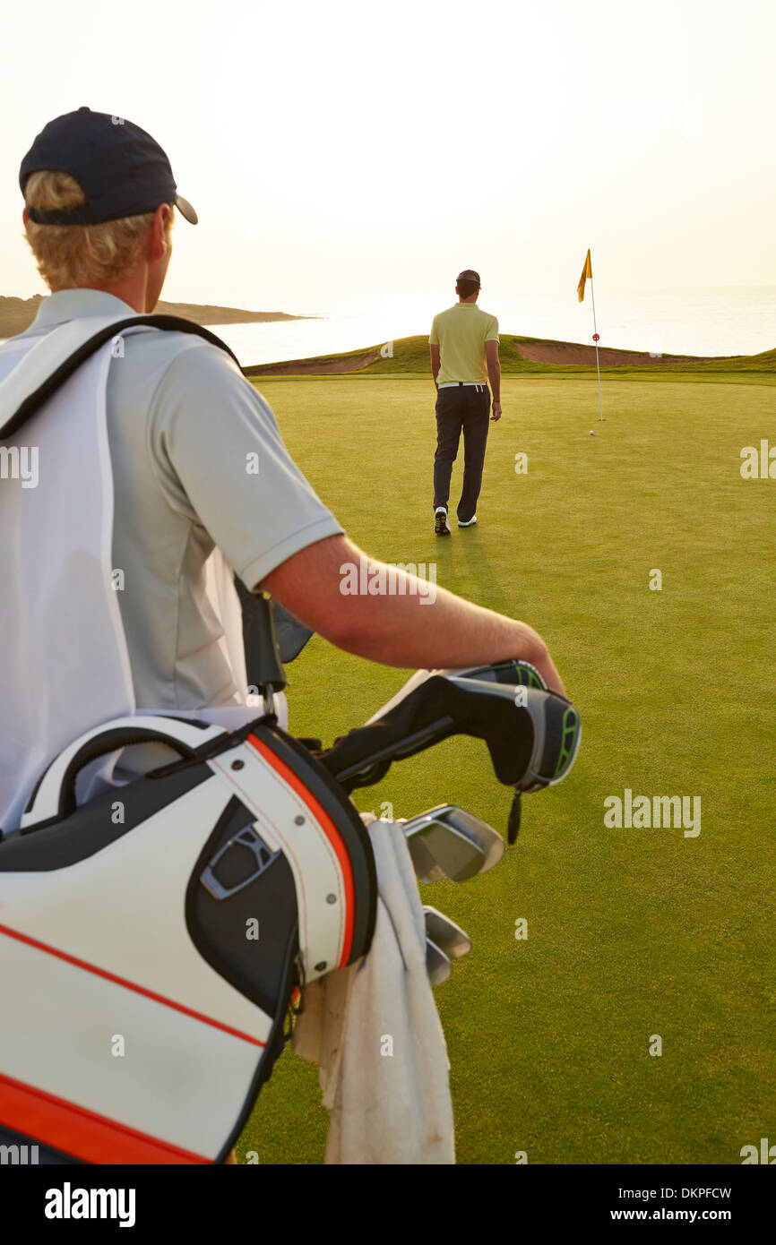 Golfer and caddy nearing golf flag Stock Photo