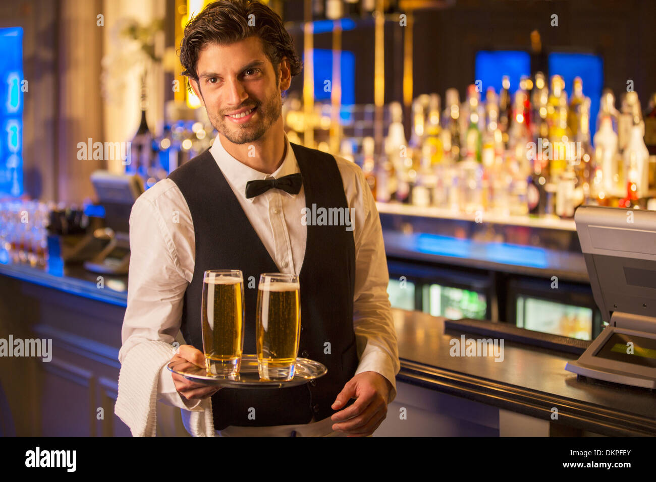 Portrait of well dressed bartender carrying beers on tray Stock Photo