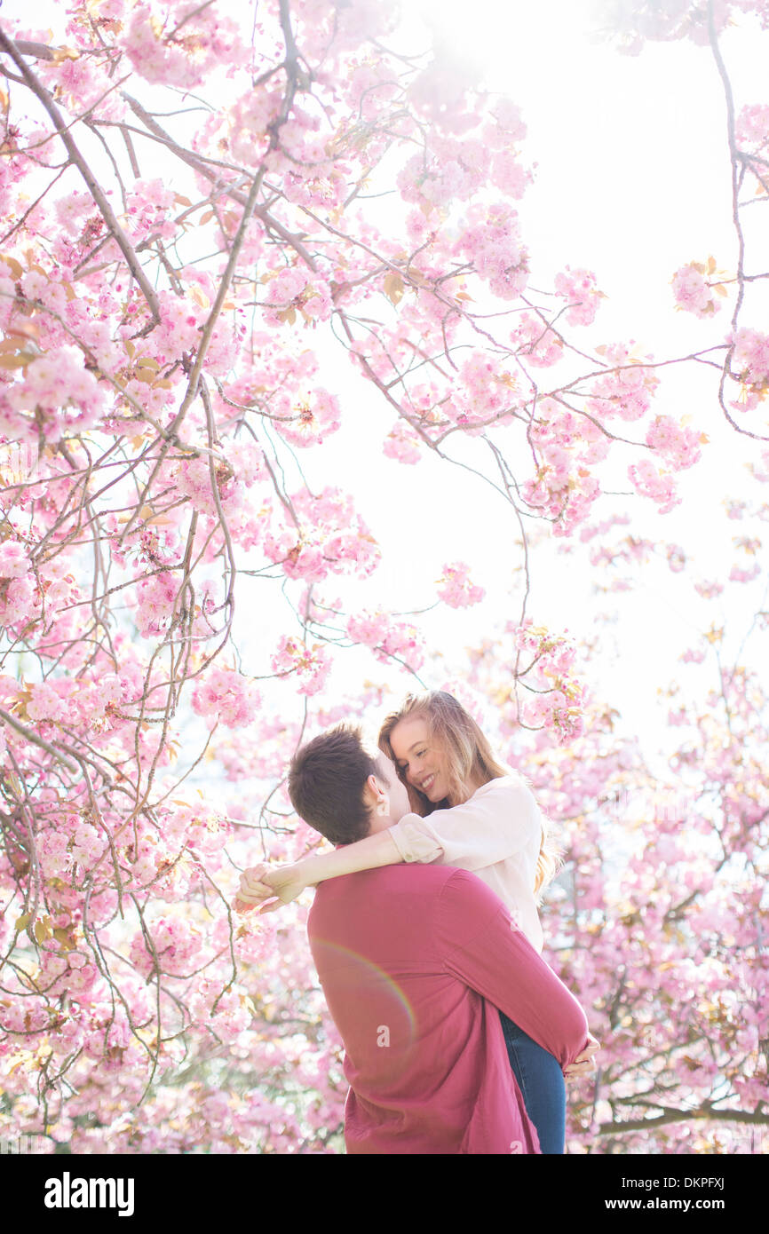 Couple hugging under tree with pink blossoms Stock Photo - Alamy