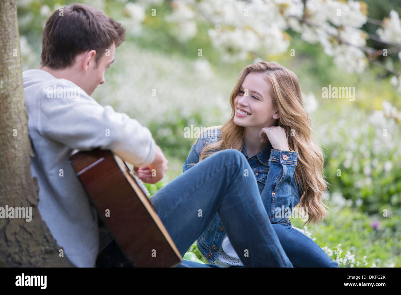 Man playing guitar for girlfriend outdoors Stock Photo