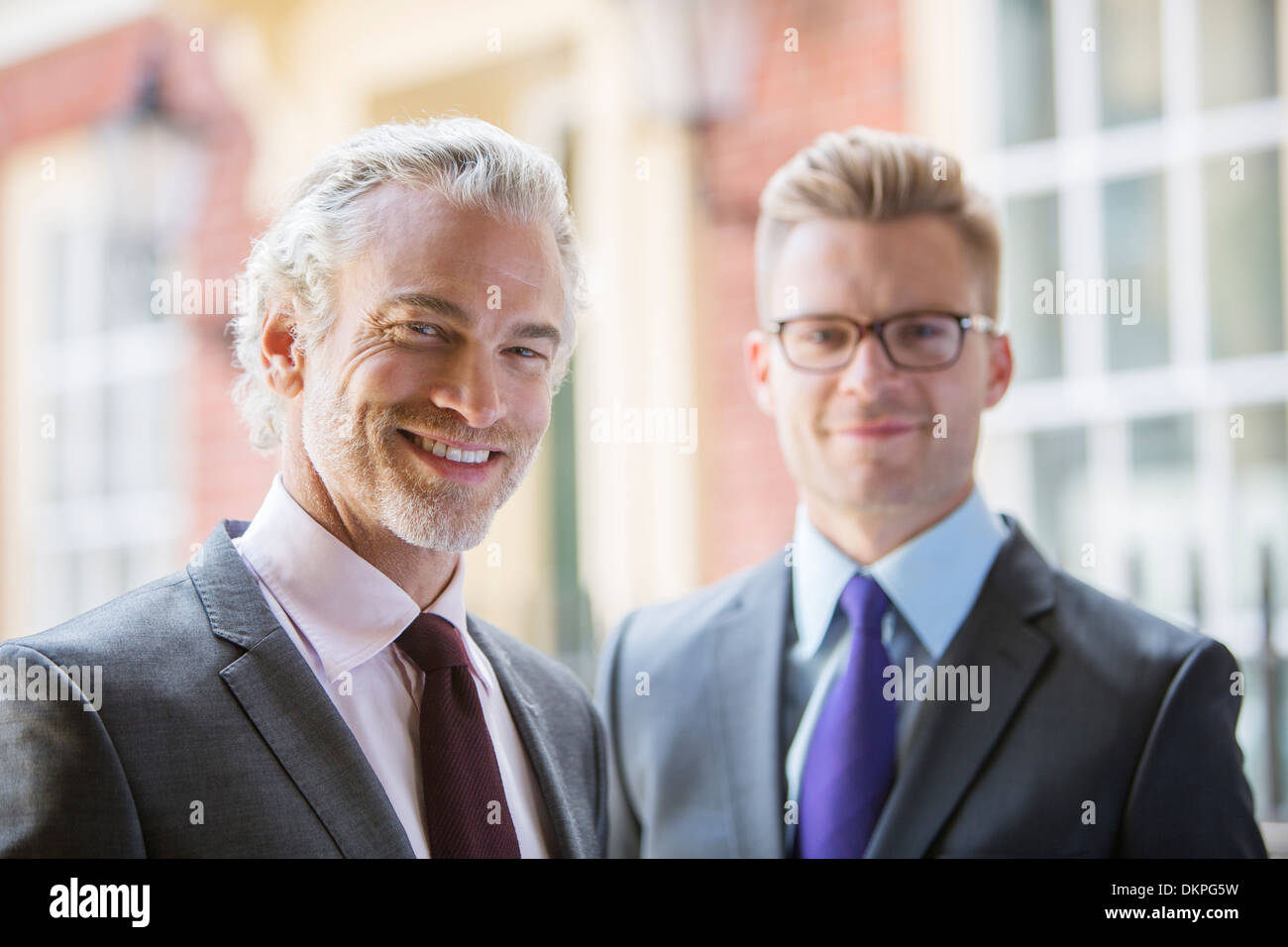 Businessmen smiling on city street Stock Photo