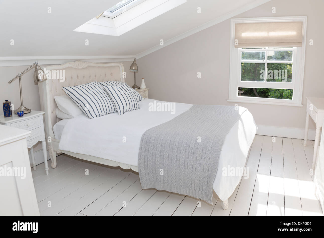 Bed in whitewashed attic bedroom Stock Photo