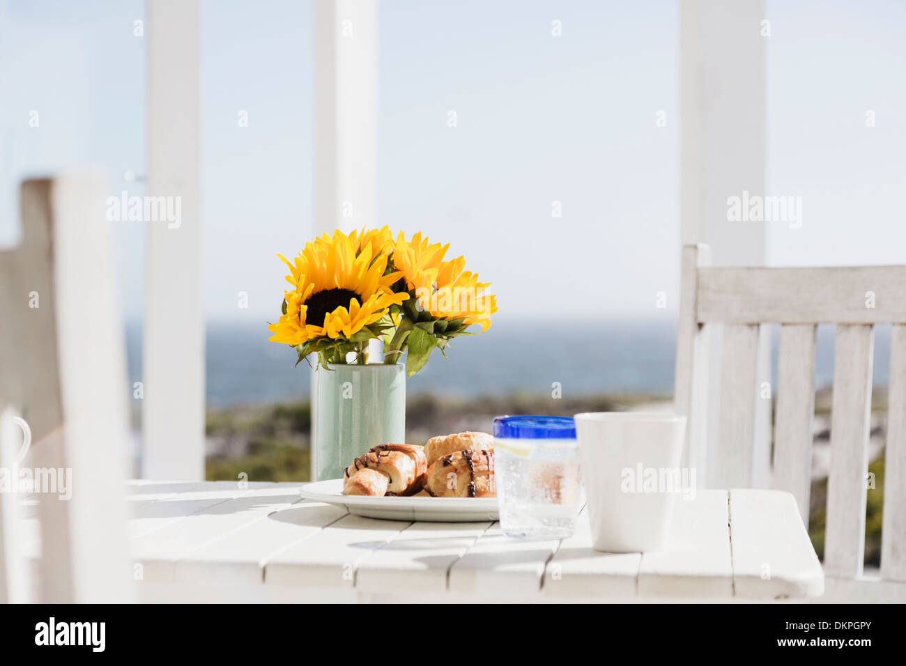 Sunflowers and croissants on patio table Stock Photo