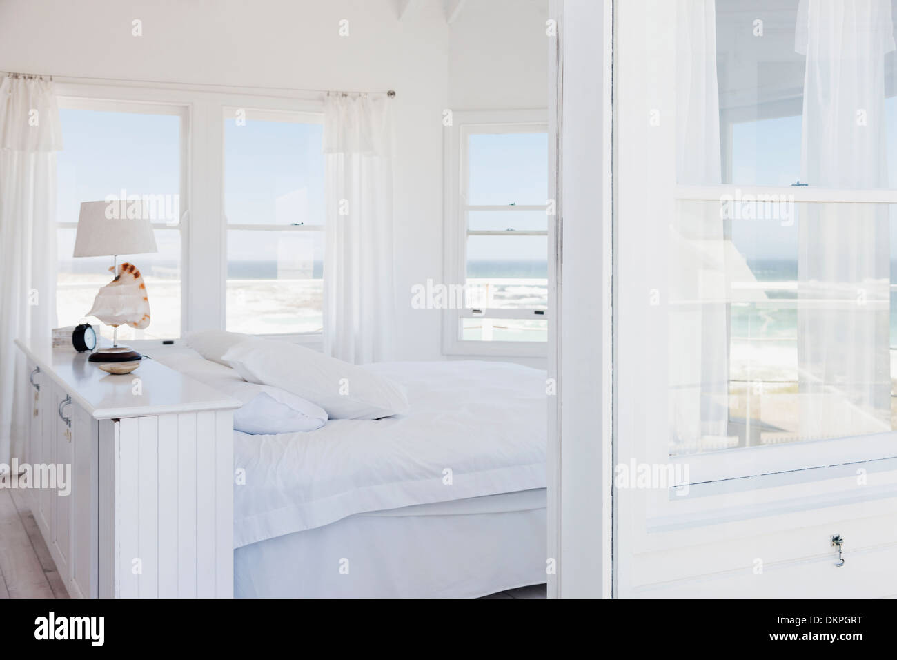 White bedroom overlooking ocean Stock Photo