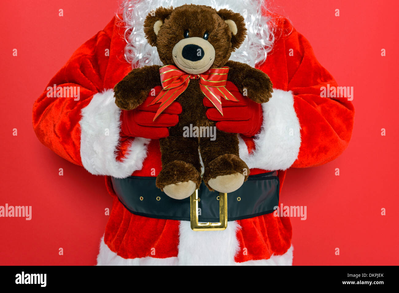 Santa Claus or Father Christmas holding a handmade teddy bear with bow. Stock Photo
