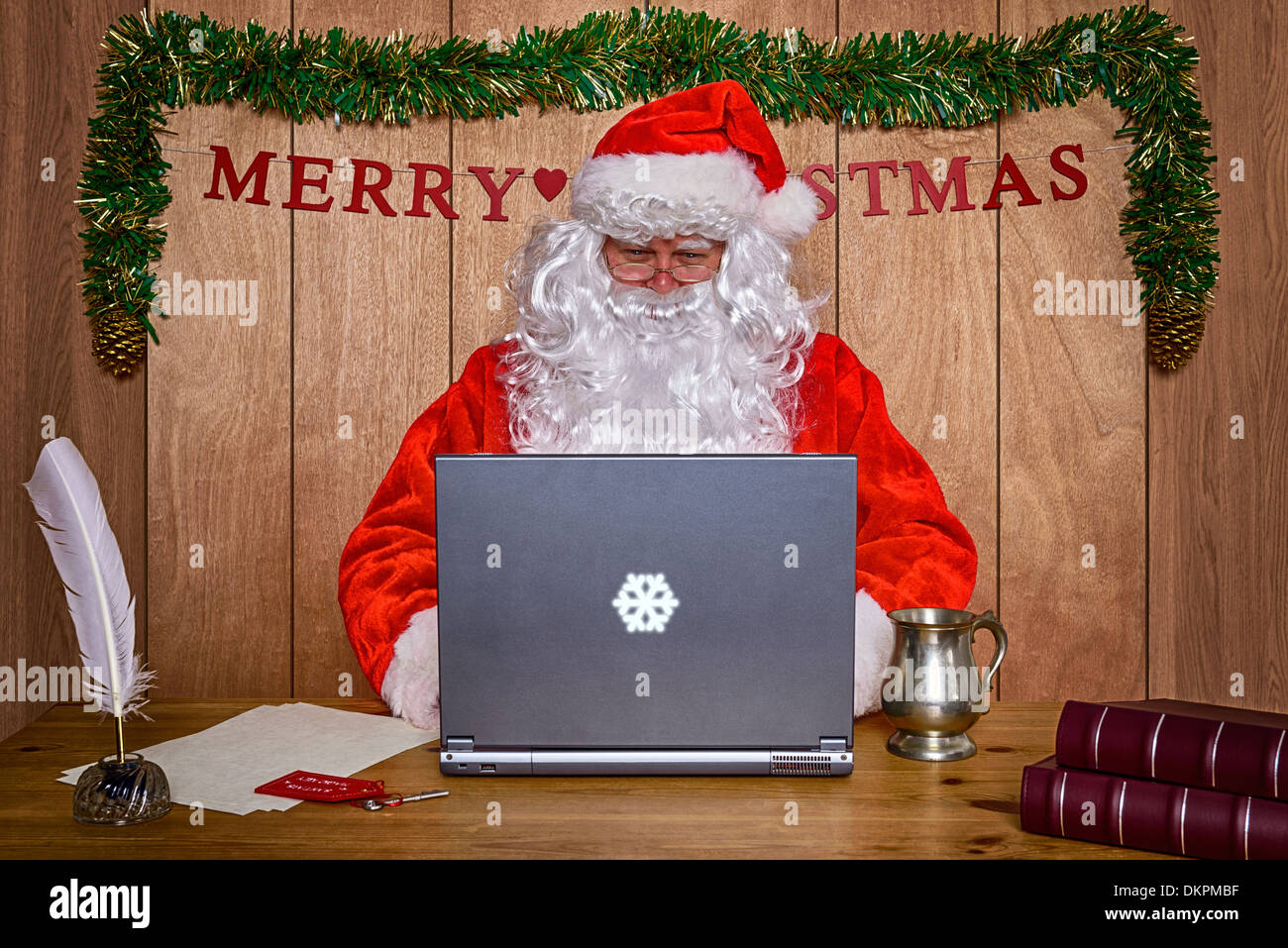 Santa sat at his desk in the North Pole doing some online Christmas shopping and answering his emails. Stock Photo
