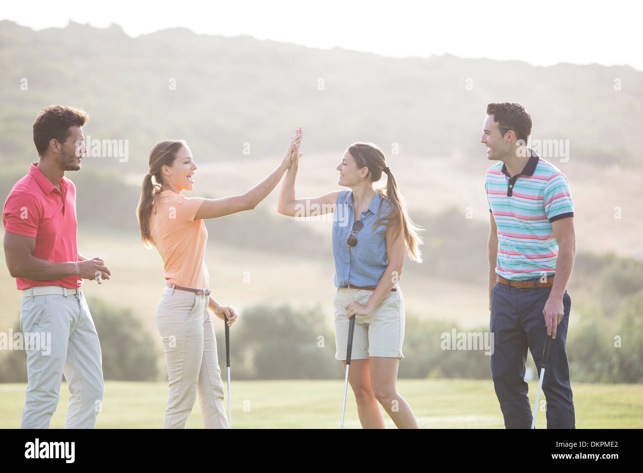 Friends high fiving on golf course Stock Photo