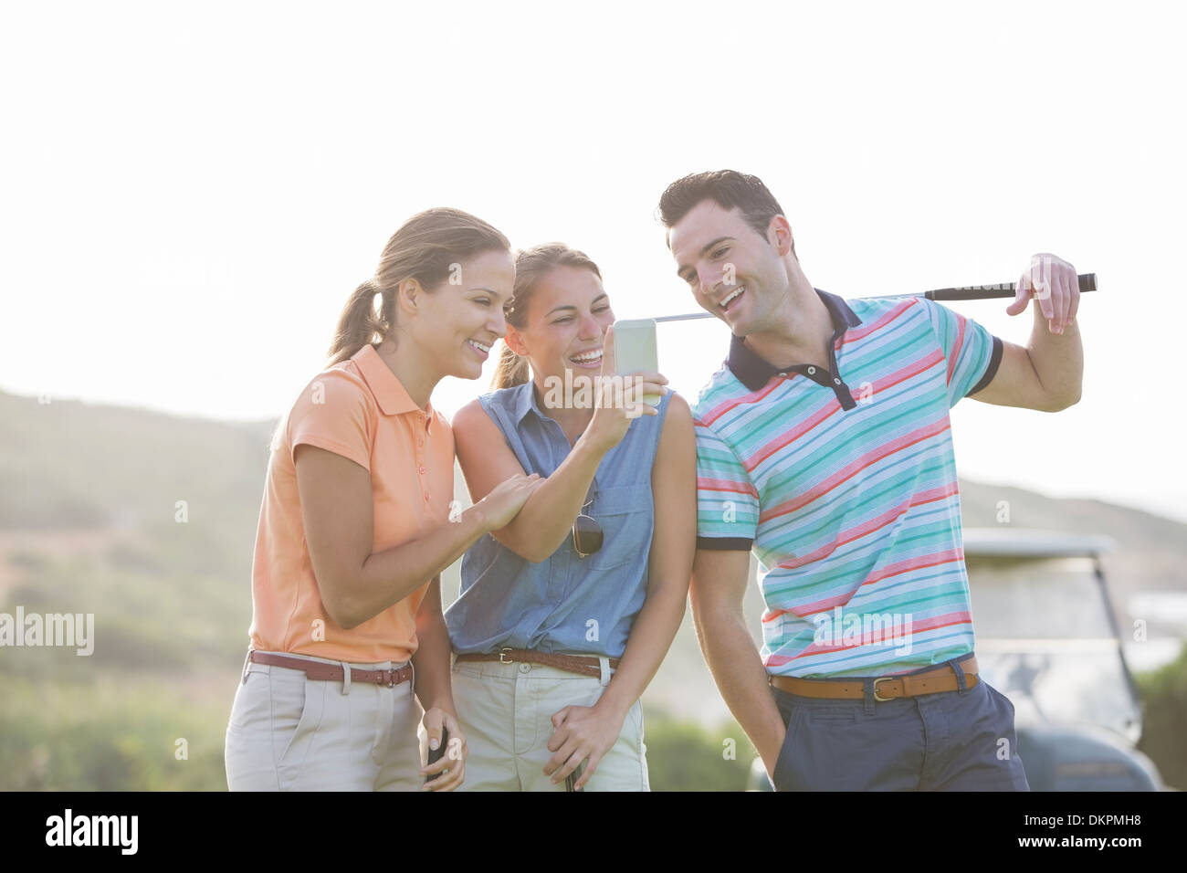 Friends looking at cell phone on golf course Stock Photo