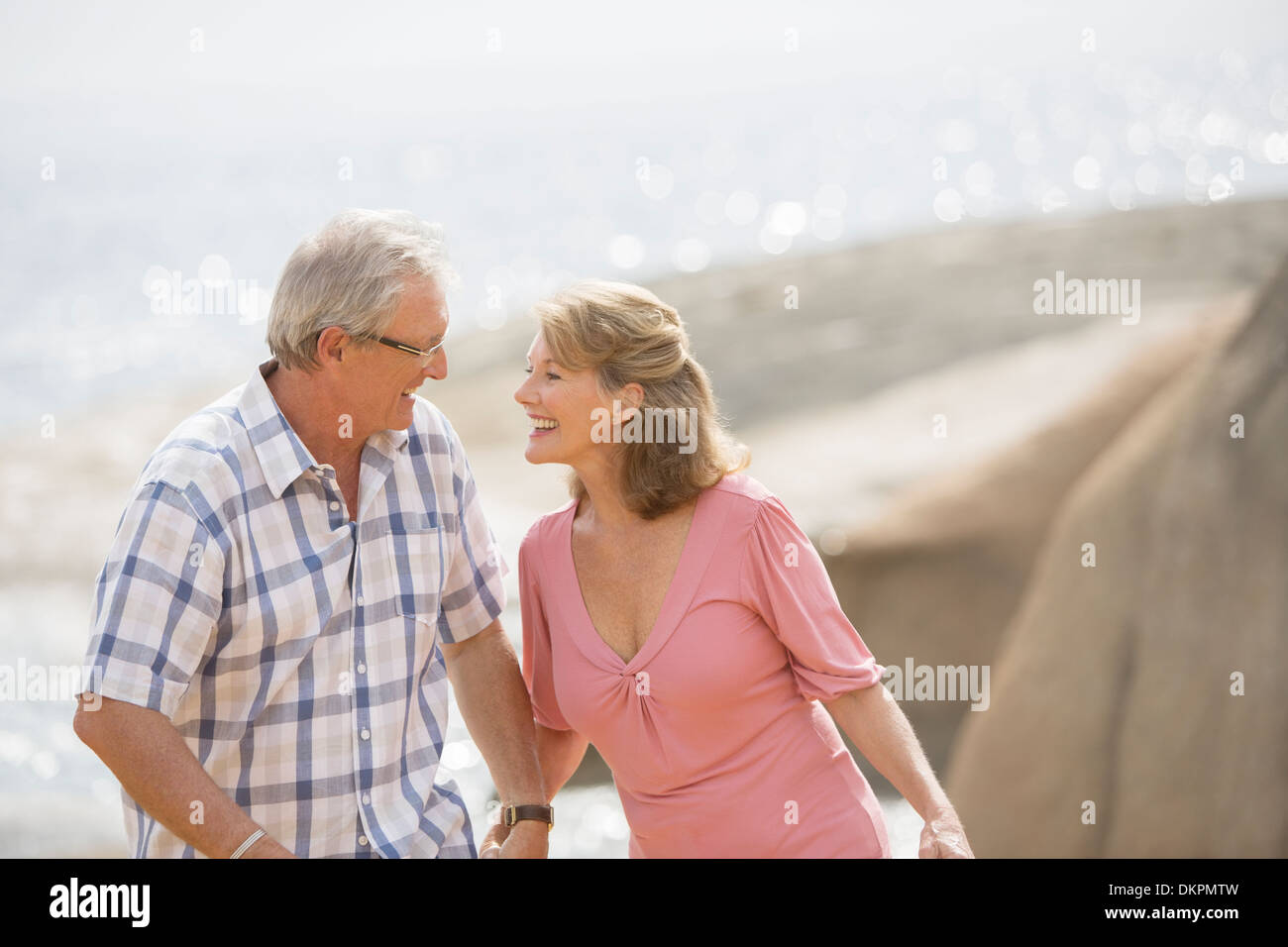 Older couple holding hands on beach Stock Photo