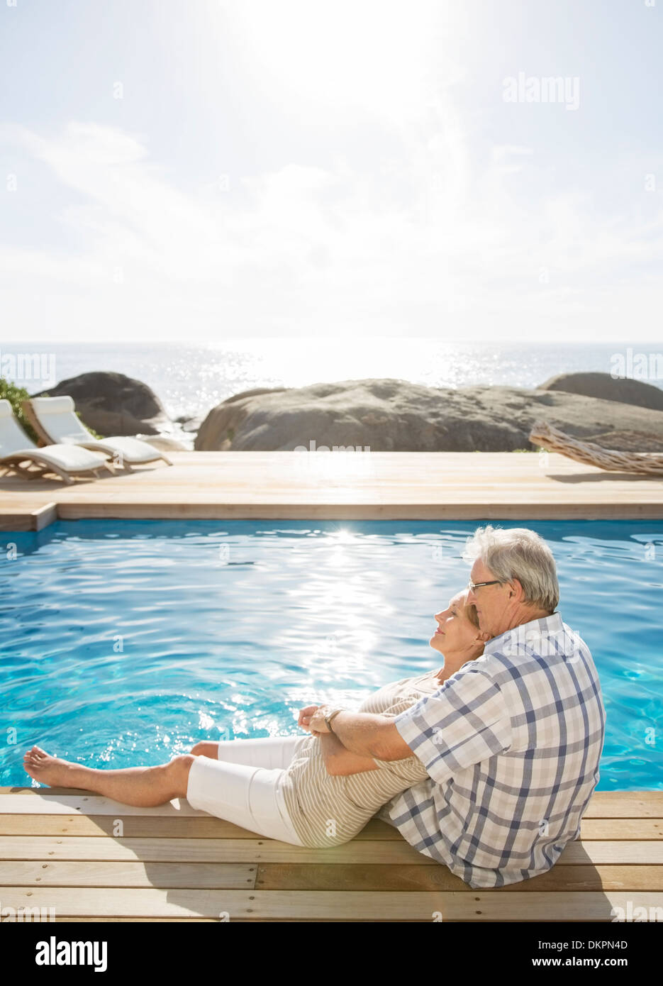 Older couple relaxing by pool Stock Photo