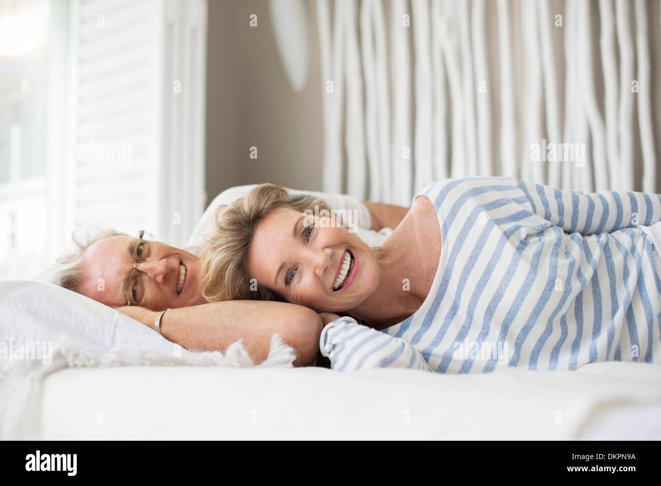 Older couple relaxing together on bed Stock Photo