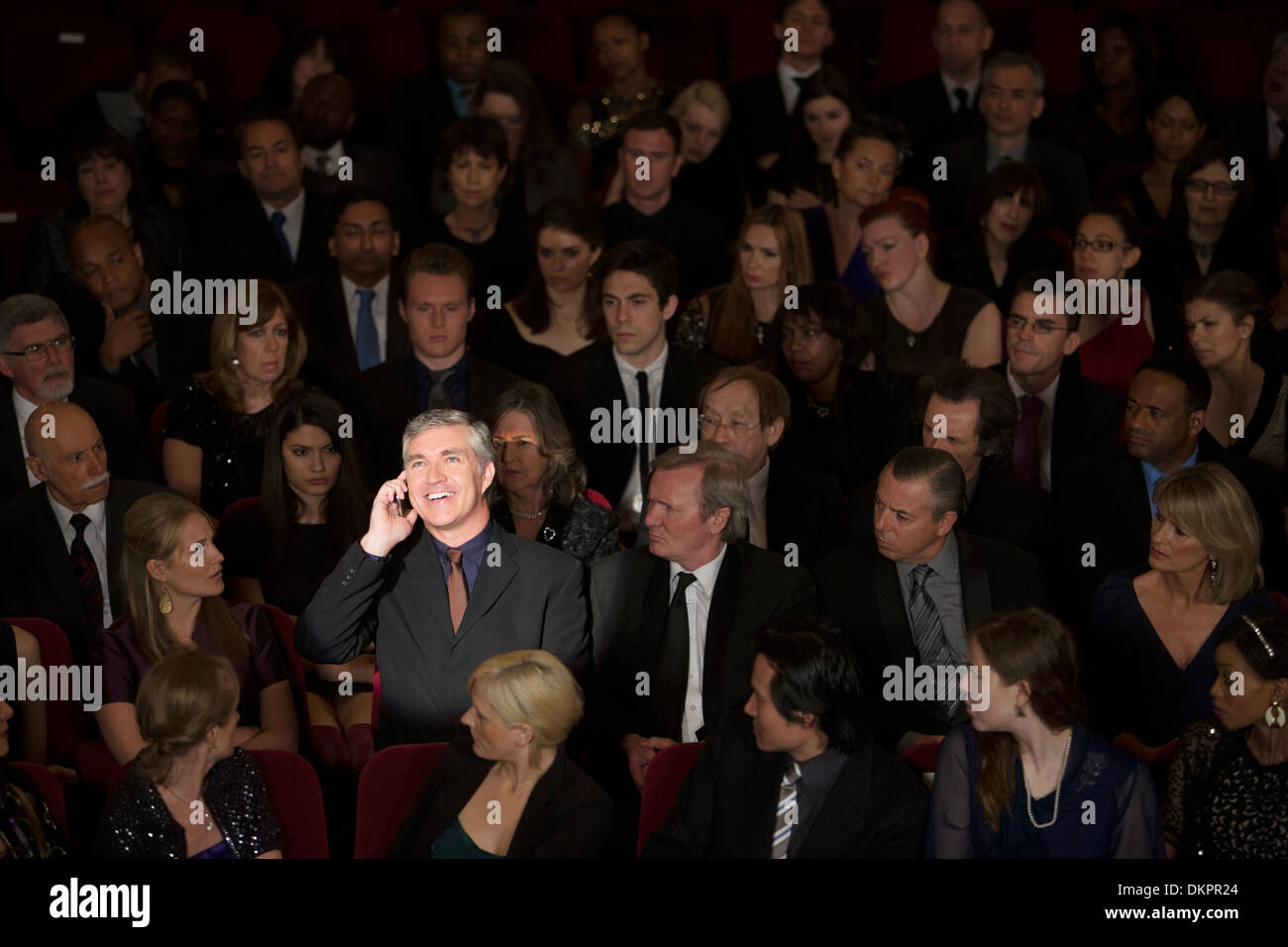 Man talking on cell phone in theater audience Stock Photo