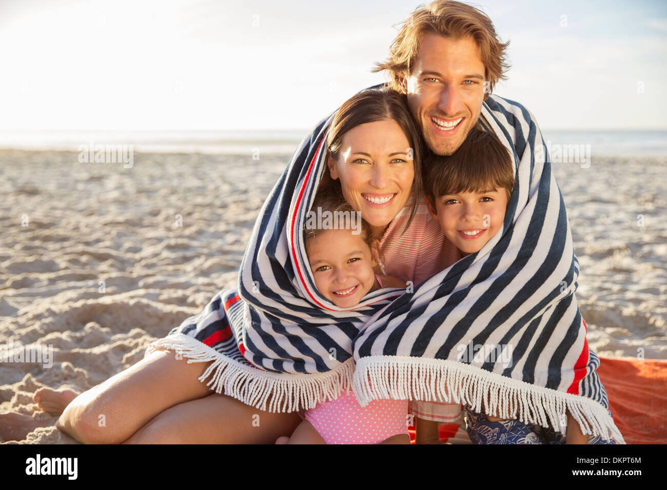 Family wrapped in blanket on beach Stock Photo