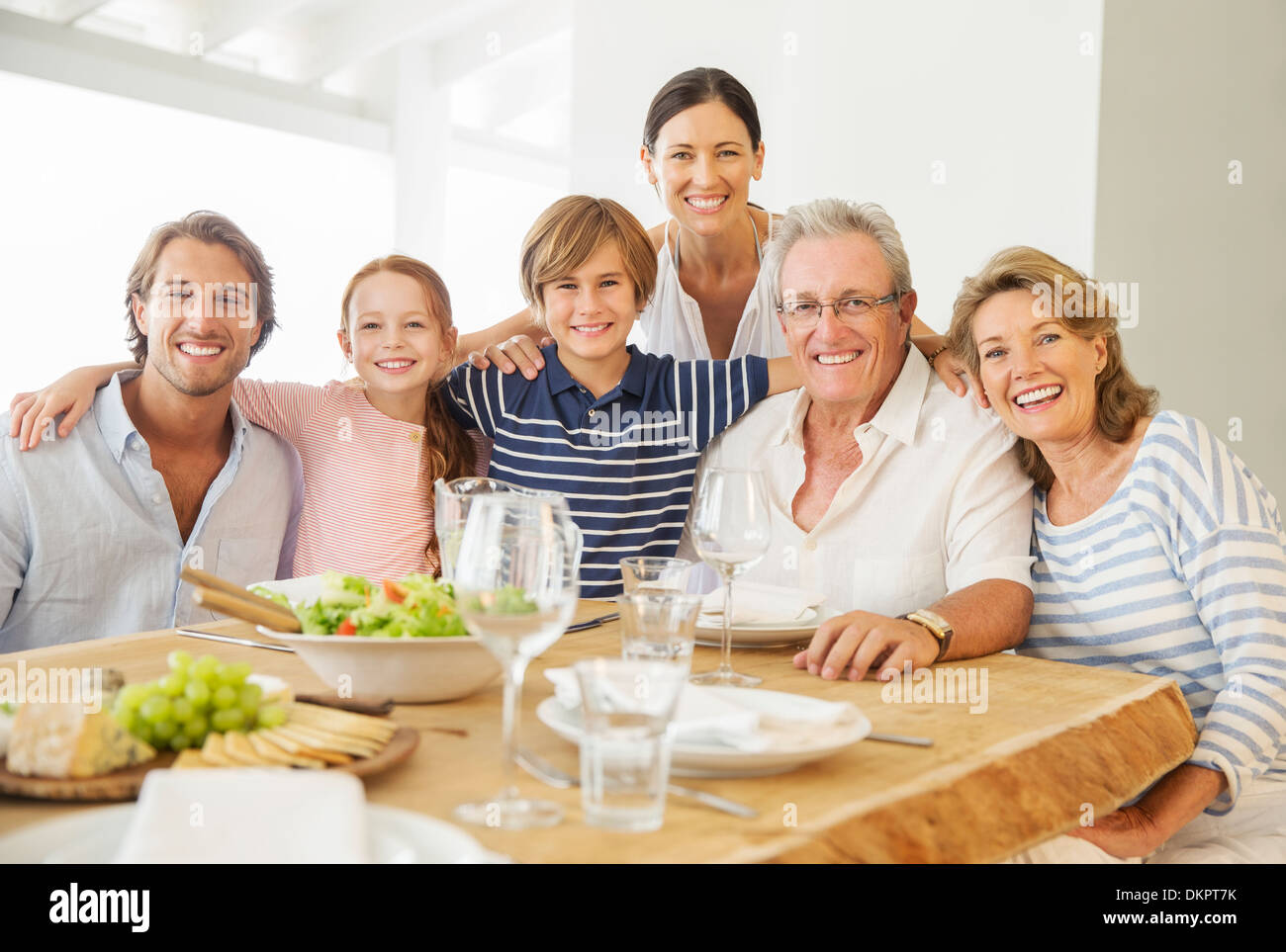 Multi-generation family smiling together at table Stock Photo