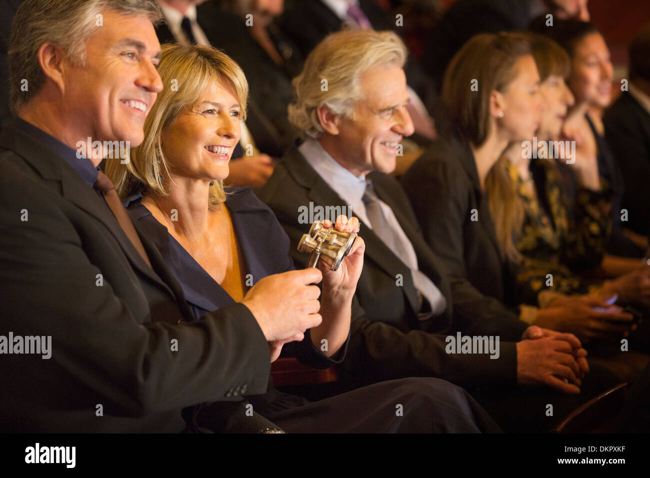 Smiling couple holding opera glasses in theater audience Stock Photo