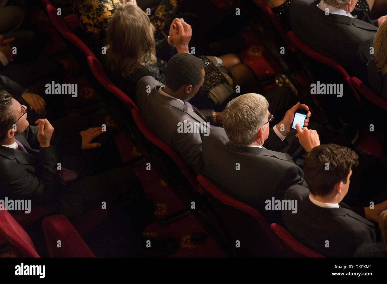 Man using cell phone in theater audience Stock Photo