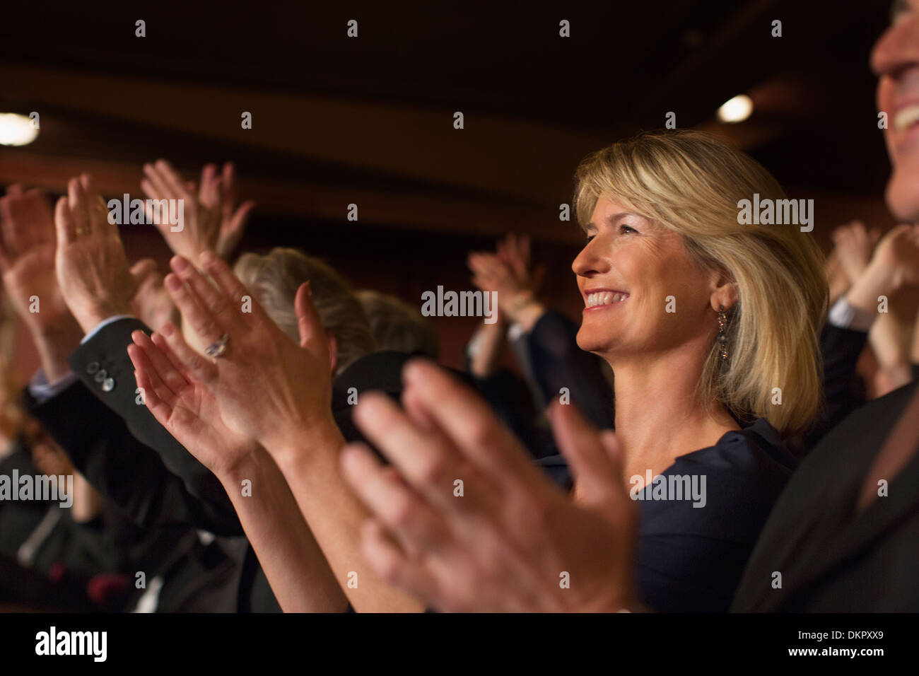 Close up of enthusiastic woman clapping in theater audience Stock Photo