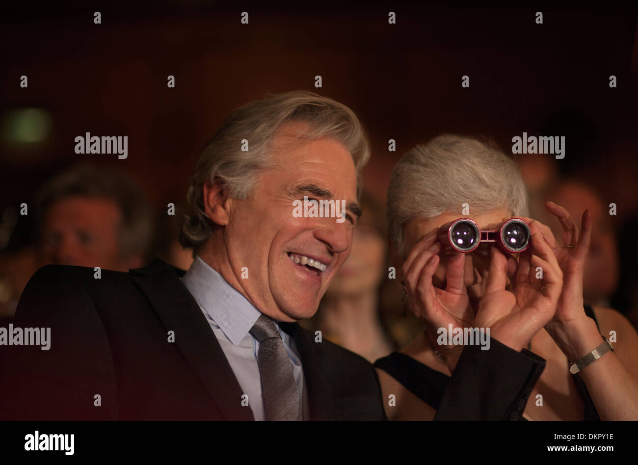 Close up of smiling couple using opera glasses in theater audience Stock Photo