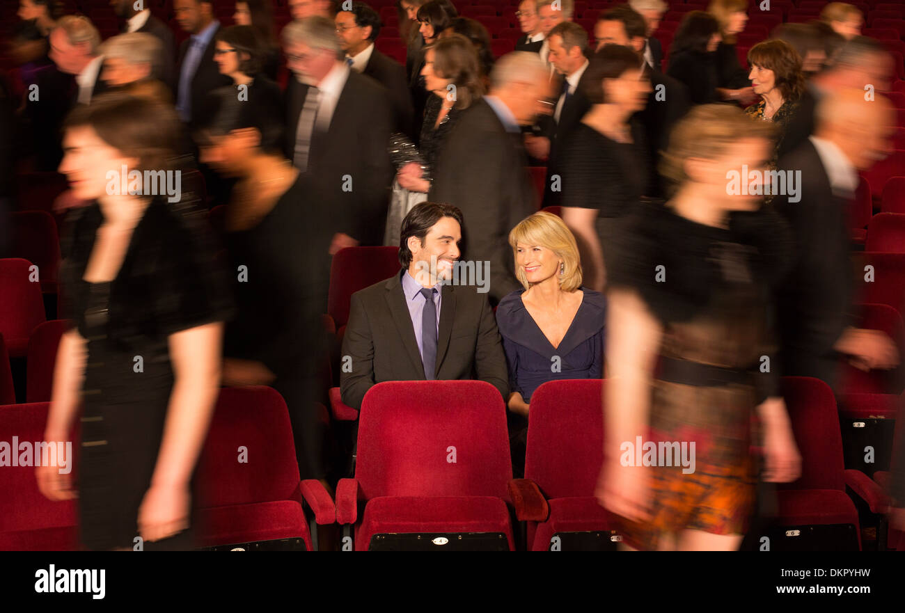 Couple sitting among people leaving theater Stock Photo