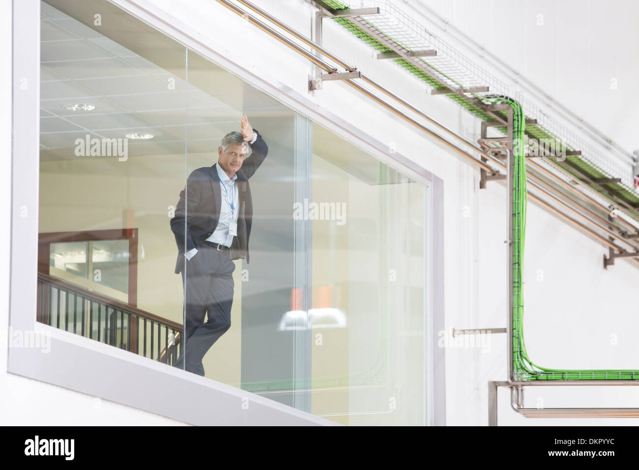 Supervisor leaning on glass window in warehouse Stock Photo