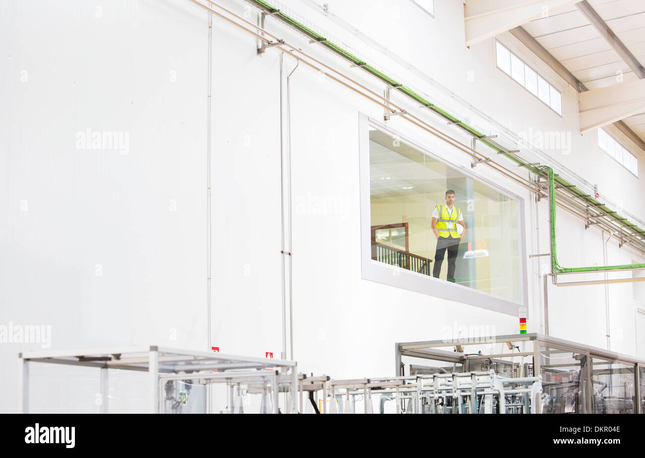 Worker looking out glass window in warehouse Stock Photo Alamy