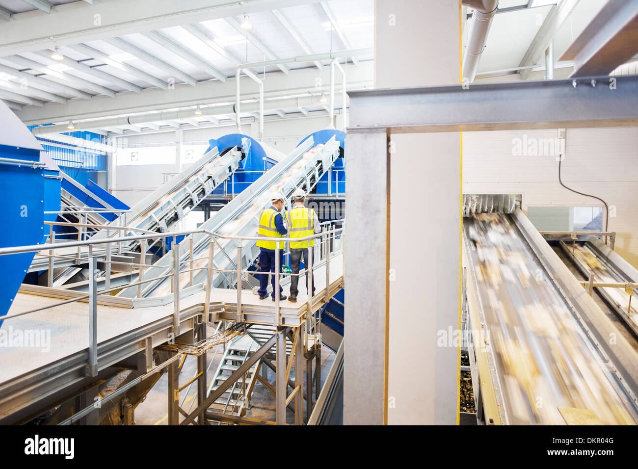 Workers talking on platform in recycling center Stock Photo