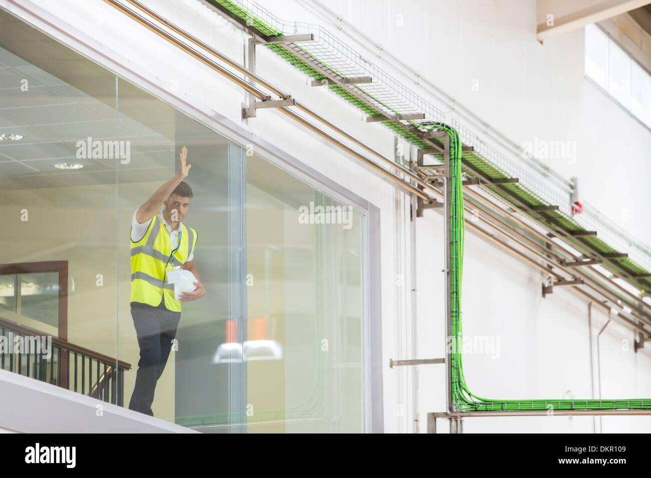 Worker leaning on observation window in factory Stock Photo - Alamy