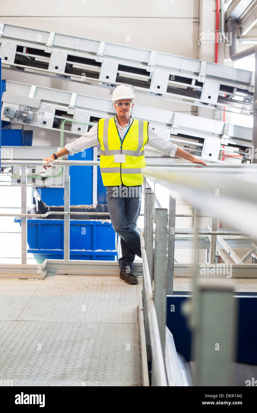 Worker leaning on platform railing in factory Stock Photo