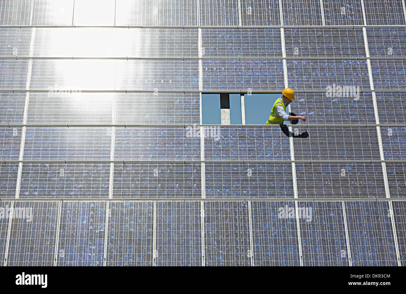 Worker examining solar panel in rural landscape Stock Photo