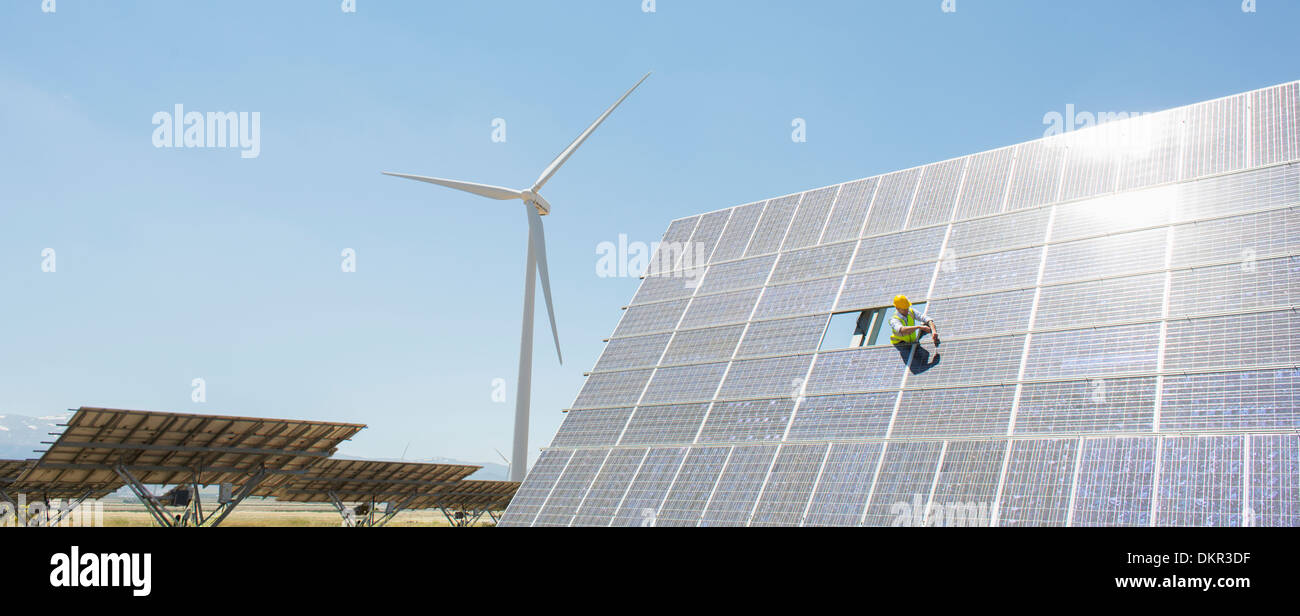 Worker examining solar panel in rural landscape Stock Photo