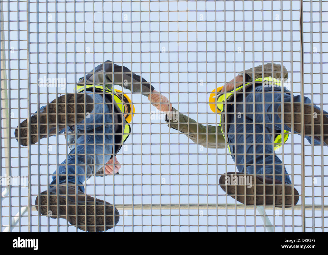 Workers shaking hands on grating Stock Photo
