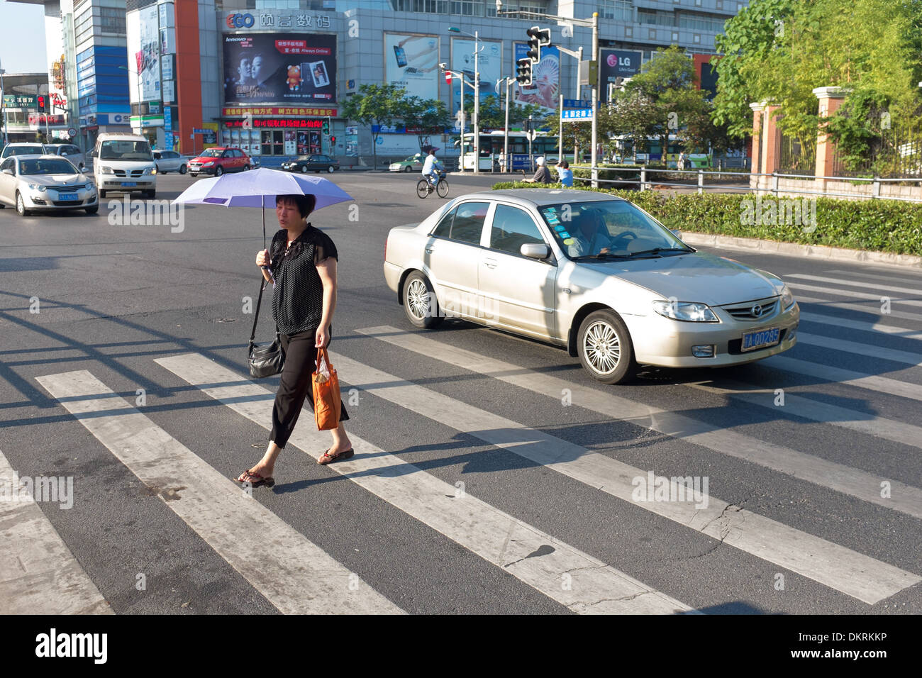 Women walking with umbrella to shade from sun on pedestrian crossing in