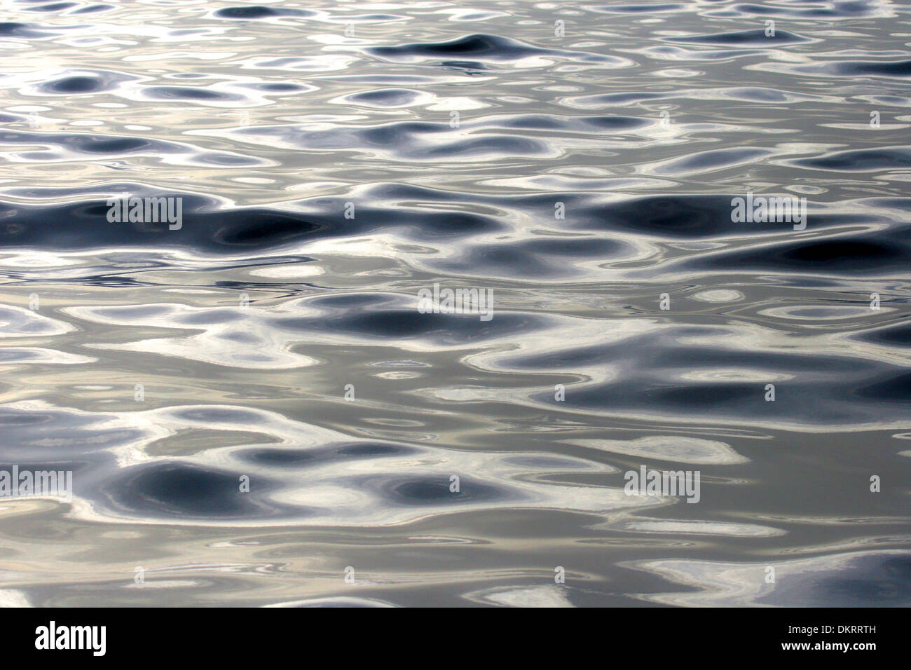 Close up of the sea with a slight ripple from waves. Dark blue with beautiful light reflecting on the surface. Stock Photo