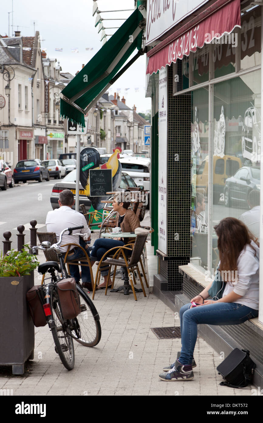 Bléré, in the Loire valley, France. Two people sitting outside the bar and one young woman sitting outside driving school. Stock Photo
