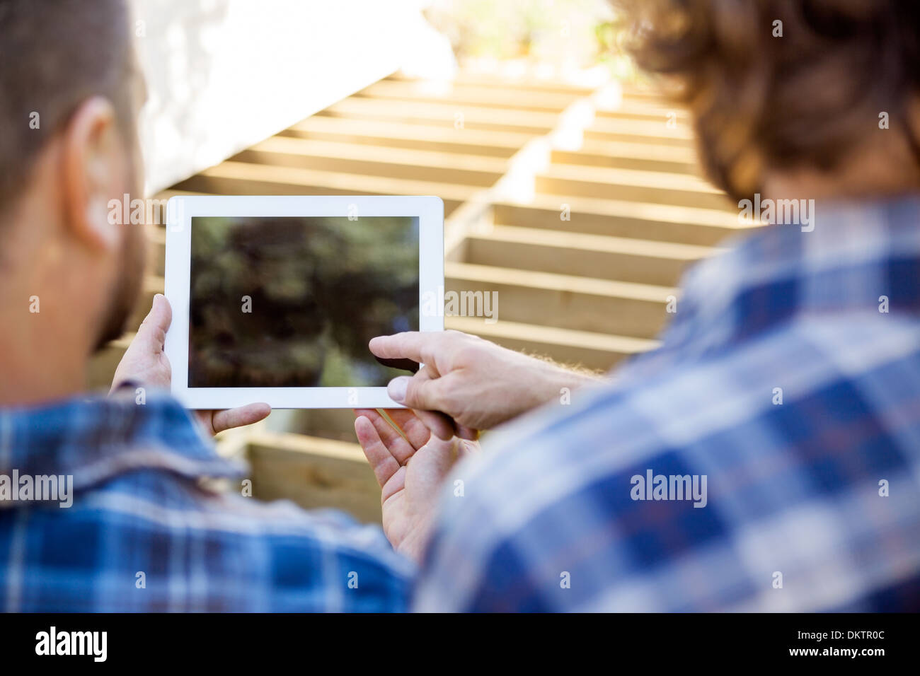 Worker Pointing At Digital Tablet While Coworker Holding It Stock Photo