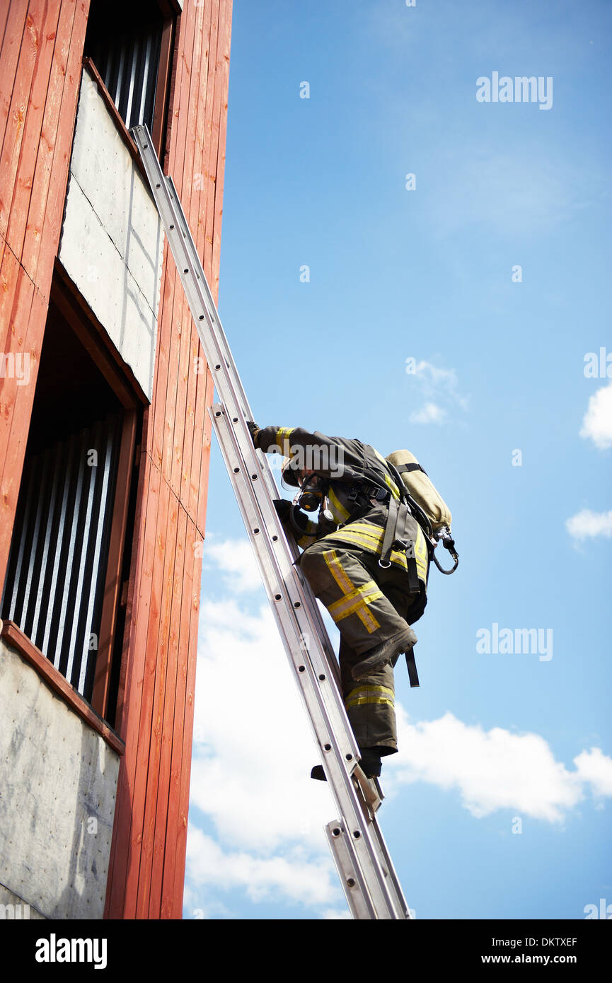 Firefighter climb on fire stairs to window Stock Photo