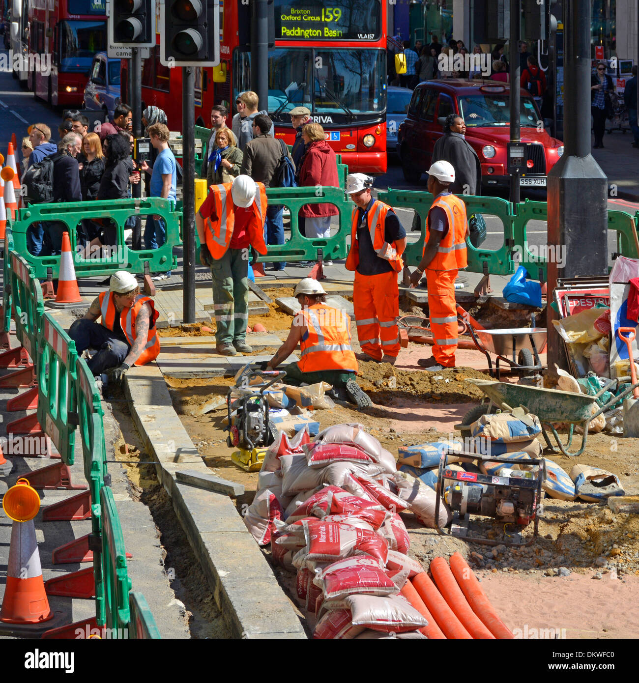 Workmen high vis carrying out alterations to kerbs at pedestrian crossing on Oxford Street West End London England UK Stock Photo