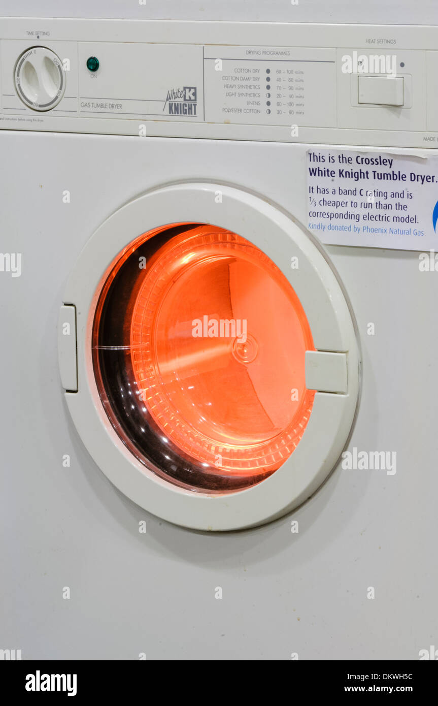 A gas powered tumble drier with the inner drum illuminated with red while in use Stock Photo