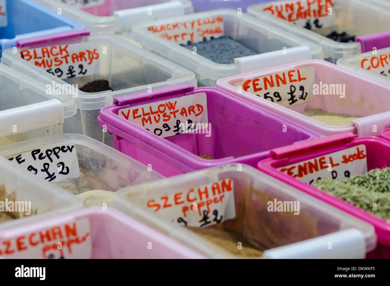 Herbs and spices in plastic containers at a market stall. Stock Photo