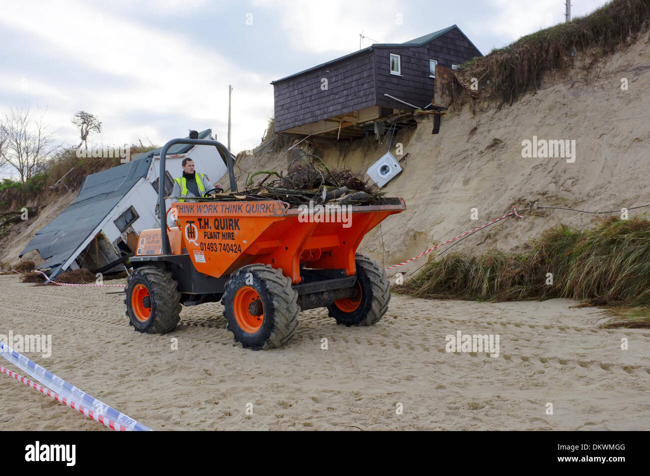 Cleanup operation in progress after Beach home collapsed down onto beach or hang precariously over edge of dunes caused by unusually high tidal storm surge washed away the land below it. Scene on Sunday 8th December 2013 Stock Photo